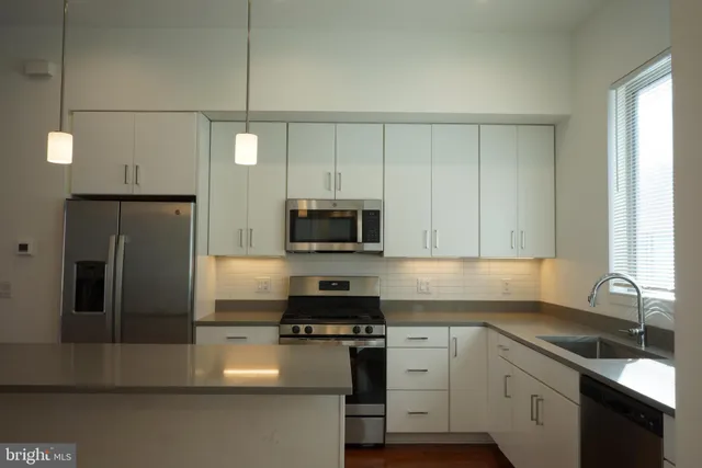 a kitchen with a sink a microwave a refrigerator and cabinets