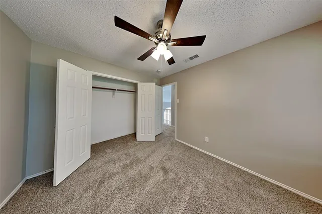an empty room with closet and ceiling fan