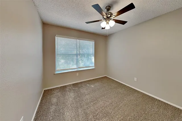 an empty room with windows and ceiling fan