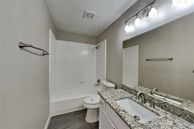a bathroom with a granite countertop sink a toilet and shower