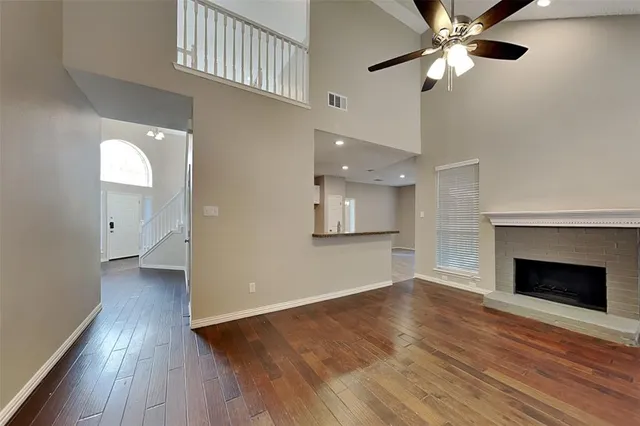 an empty room with wooden floor a ceiling fan and fireplace