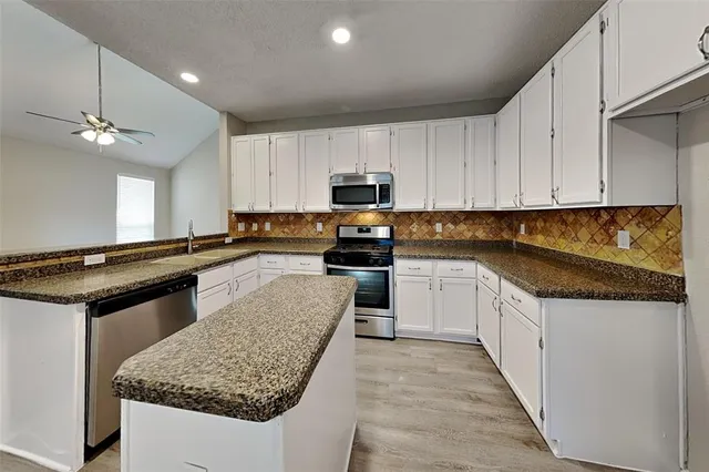 a kitchen with granite countertop a sink a counter top space stainless steel appliances and cabinets