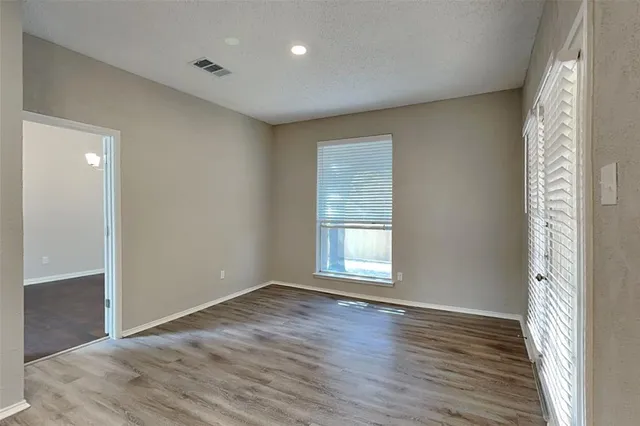 a view of an empty room with wooden floor and a window