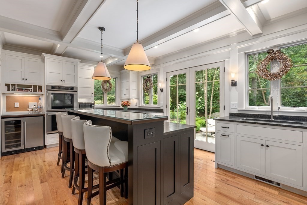 103 Conant Road Weston, MA 02493 - Photo 12 of 42 a kitchen with stainless steel appliances granite countertop a stove a refrigerator a sink dishwasher a dining table and chairs with wooden floor