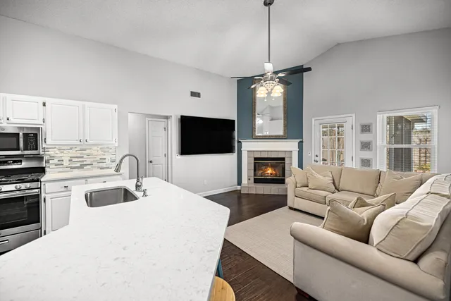 a kitchen with a refrigerator a stove a sink and white cabinets with wooden floor