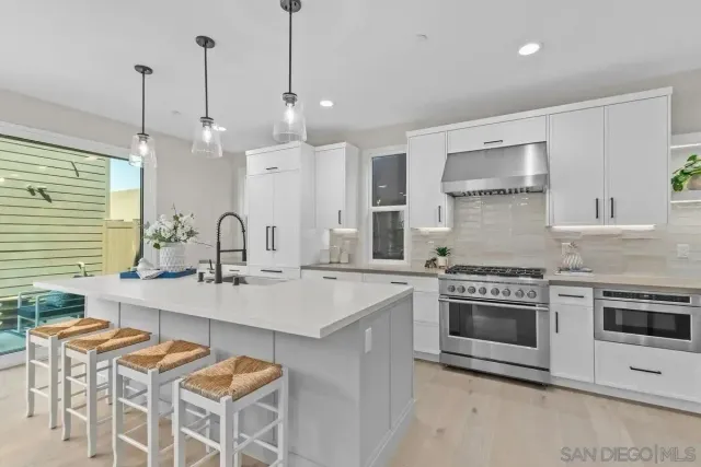a kitchen with stainless steel appliances a stove a sink a oven a counter space and white cabinets
