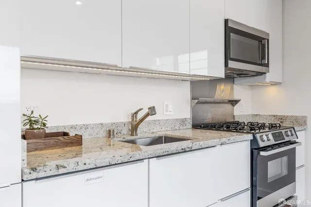 a kitchen with stainless steel appliances granite countertop a sink stove top oven and microwave