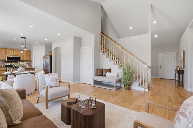 1252 Skyline Road Saratoga Springs, UT 84045 - Photo 11 of 51 Expansive living area featuring light wood-finish flooring throughout, a grand staircase with wood railing, recessed lighting, and vaulted ceilings