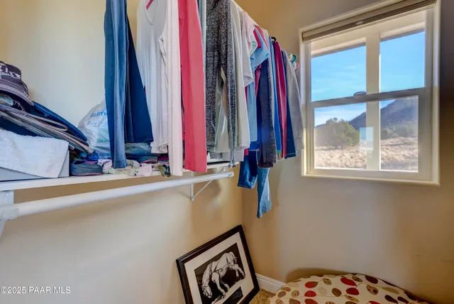 a view of a closet with clothes and shoes