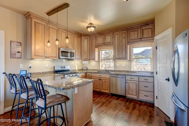 a kitchen with stainless steel appliances granite countertop a stove top oven a refrigerator a sink and white cabinets