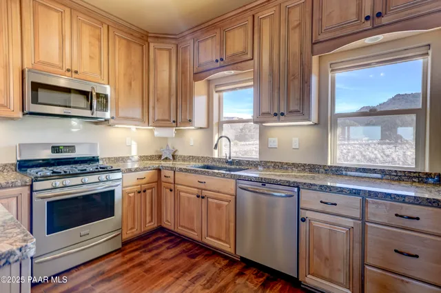 a kitchen with stainless steel appliances granite countertop a stove a sink and a microwave