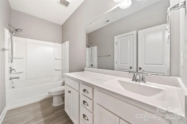 a bathroom with a granite countertop sink a toilet a large mirror a bathtub and shower