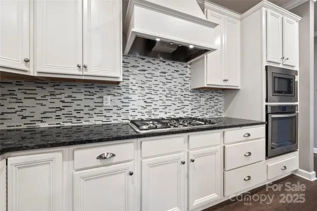 a kitchen with granite countertop white cabinets and stainless steel appliances