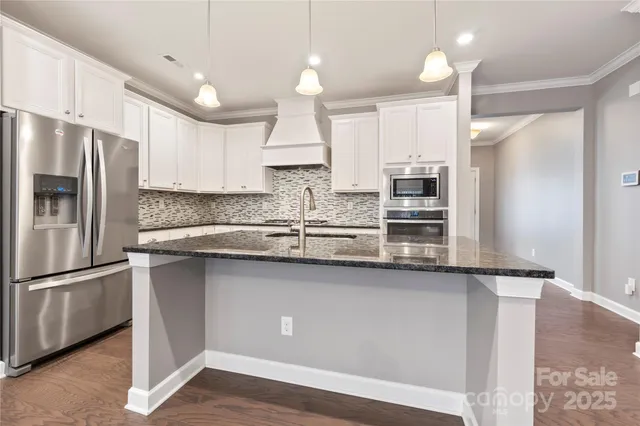 a kitchen with stainless steel appliances granite countertop a refrigerator a sink and a stove