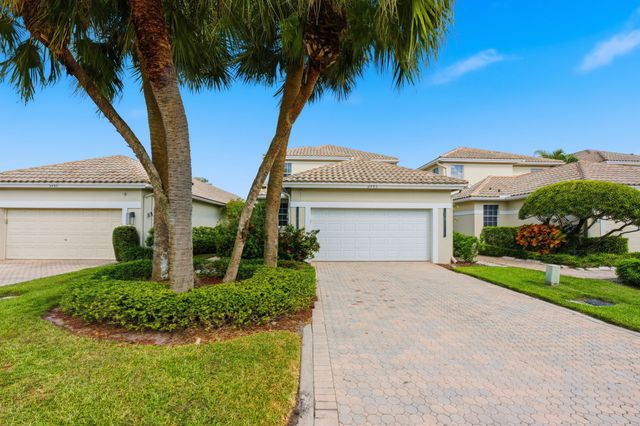 a front view of a house with a yard and palm trees