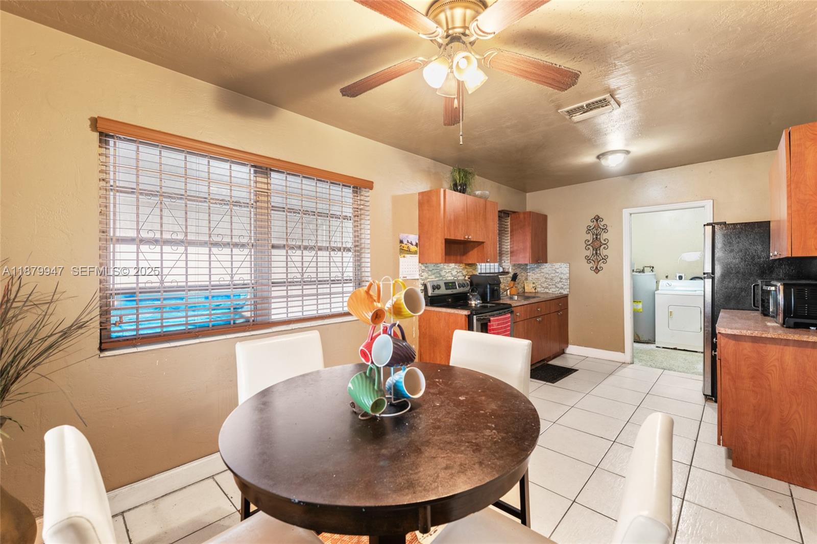 3265 Northwest 50th Street Miami, FL 33142 - Photo 6 of 17 a dining room with furniture a kitchen view and a chandelier