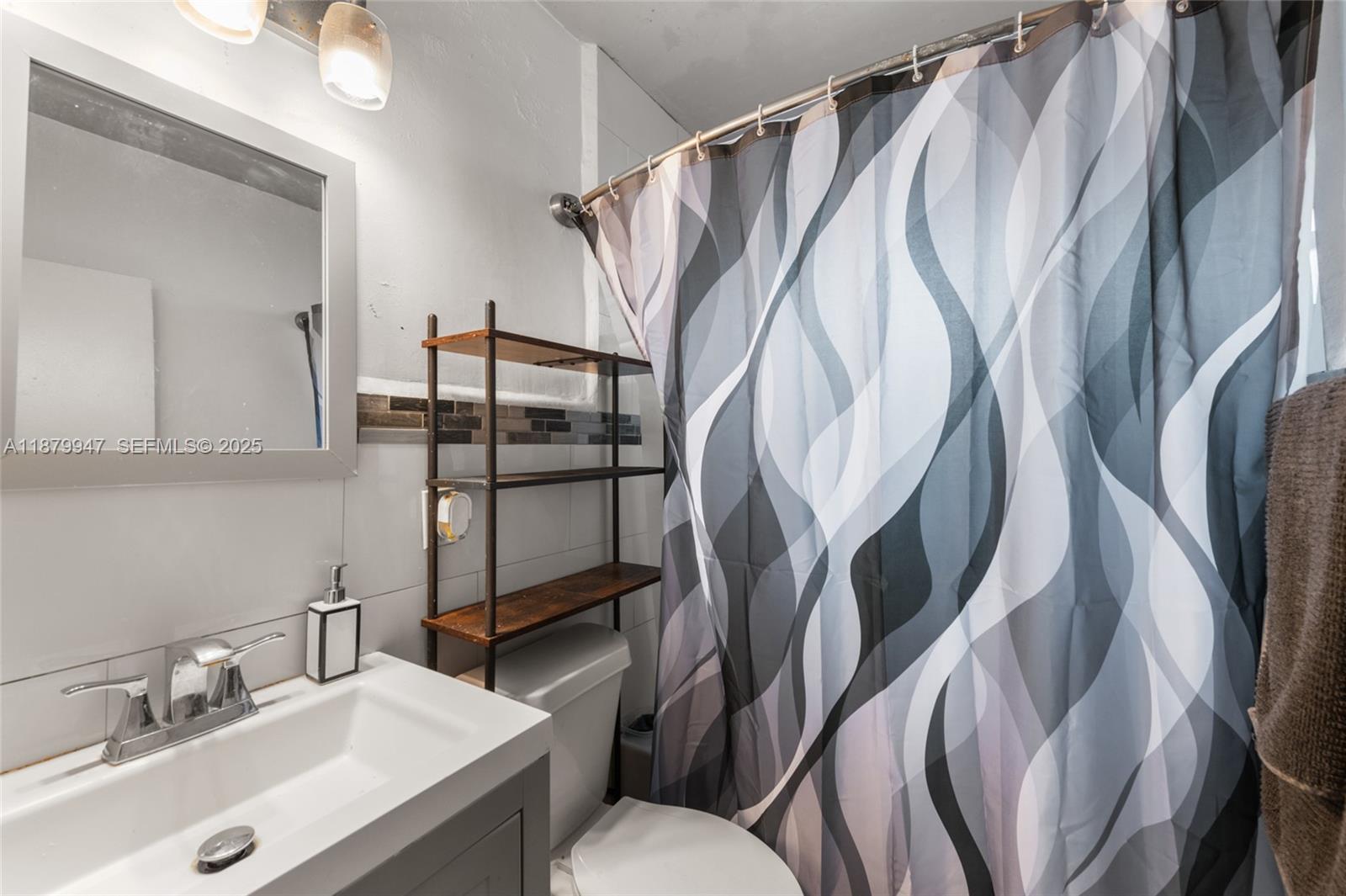3265 Northwest 50th Street Miami, FL 33142 - Photo 10 of 17 a bathroom with a sink a toilet and a mirror