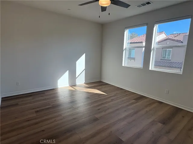 a view of an empty room with a window and wooden floor