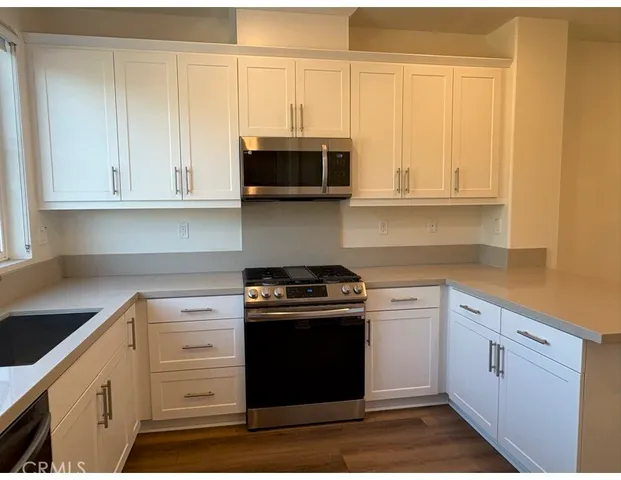 a kitchen with granite countertop white cabinets and stainless steel appliances