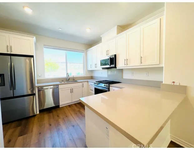 a kitchen with a sink a refrigerator and white cabinets