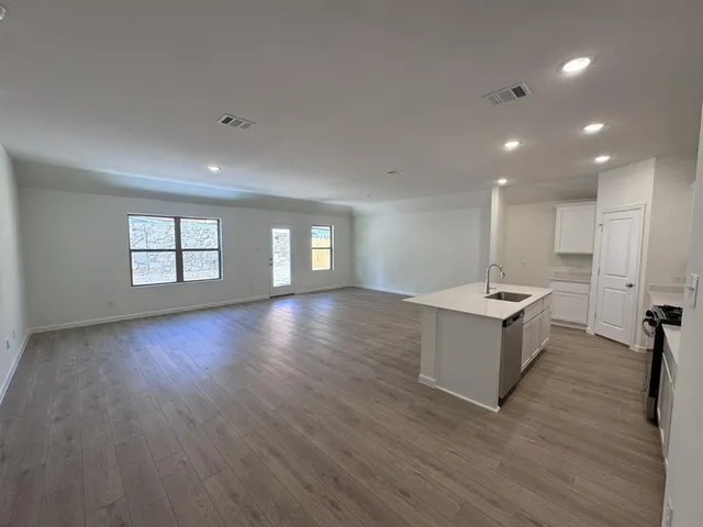 a view of an empty room with window and wooden floor
