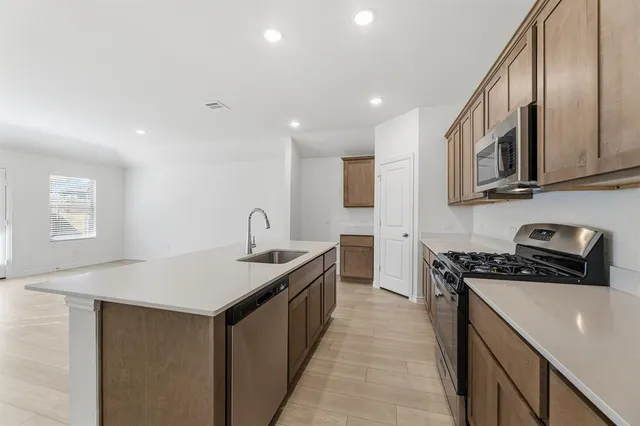 a kitchen with stainless steel appliances granite countertop a stove a sink and a refrigerator