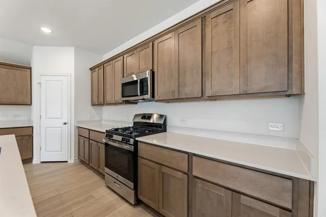 a kitchen with stainless steel appliances granite countertop a stove a sink and a microwave