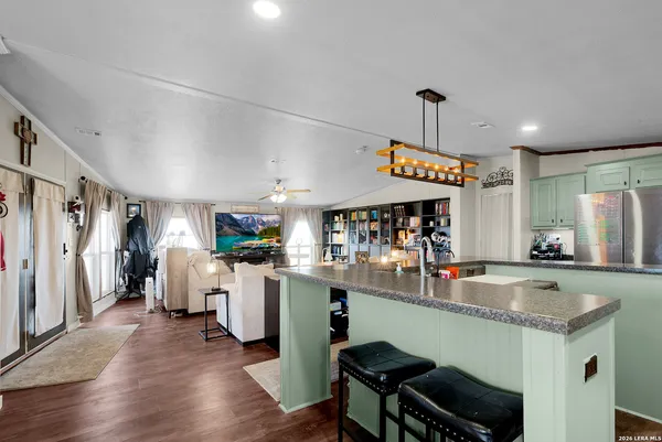a kitchen with a refrigerator a sink dishwasher a dining table and chairs with wooden floor