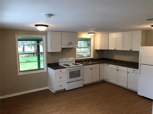 a kitchen with granite countertop white cabinets and window