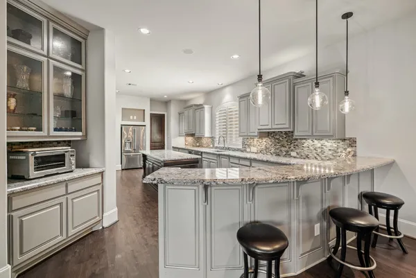 a kitchen with stainless steel appliances granite countertop a sink a stove a refrigerator and island with wooden floor