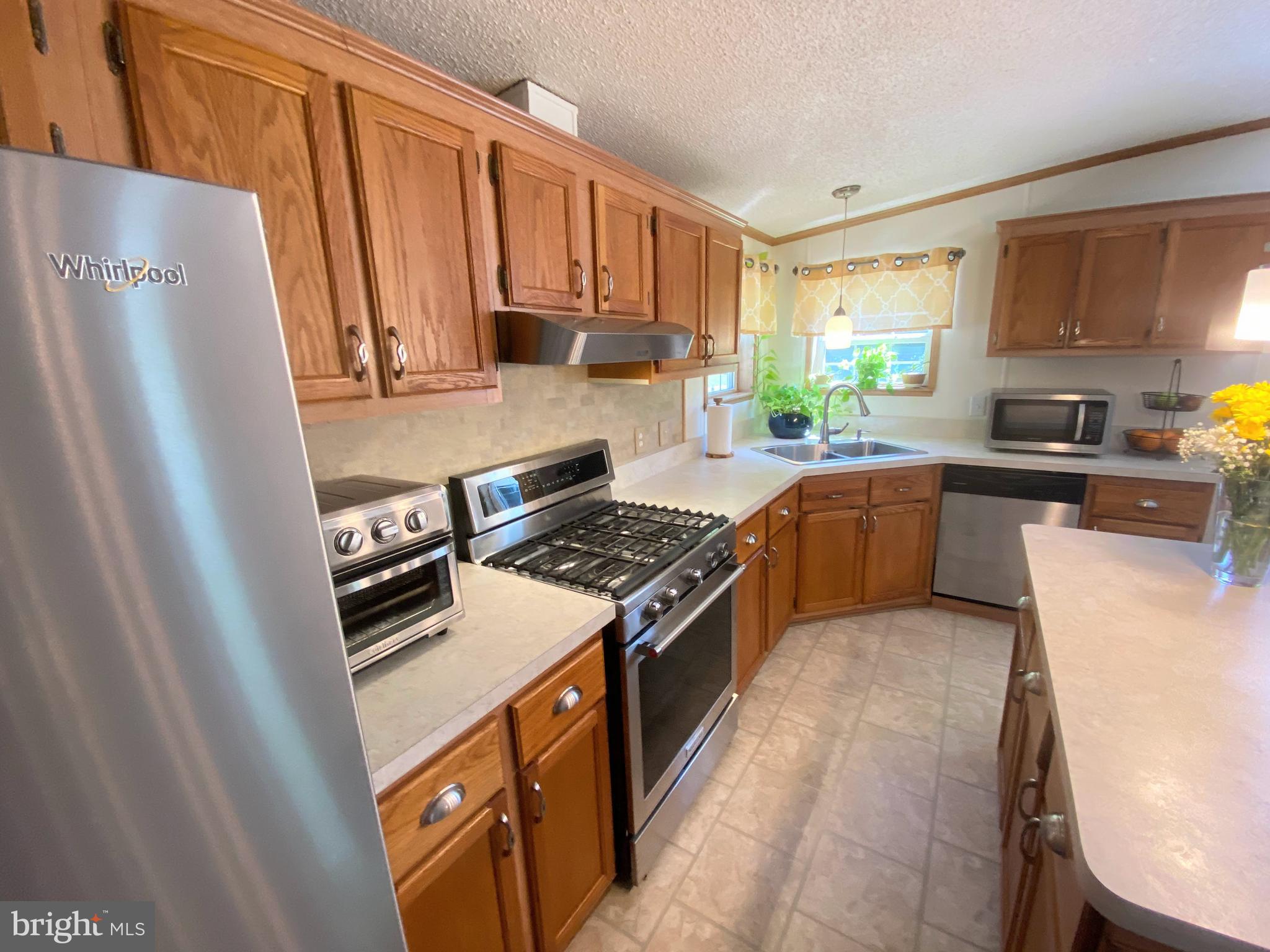 26750 North Rim Road, Unit 975 Long Neck, DE 19966 - Photo 11 of 44 a kitchen with stainless steel appliances granite countertop a refrigerator a stove a sink dishwasher and a microwave