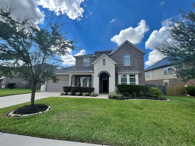 a front view of a house with garden and trees