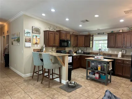 a kitchen with stainless steel appliances granite countertop a refrigerator a stove a sink a dining table and chairs