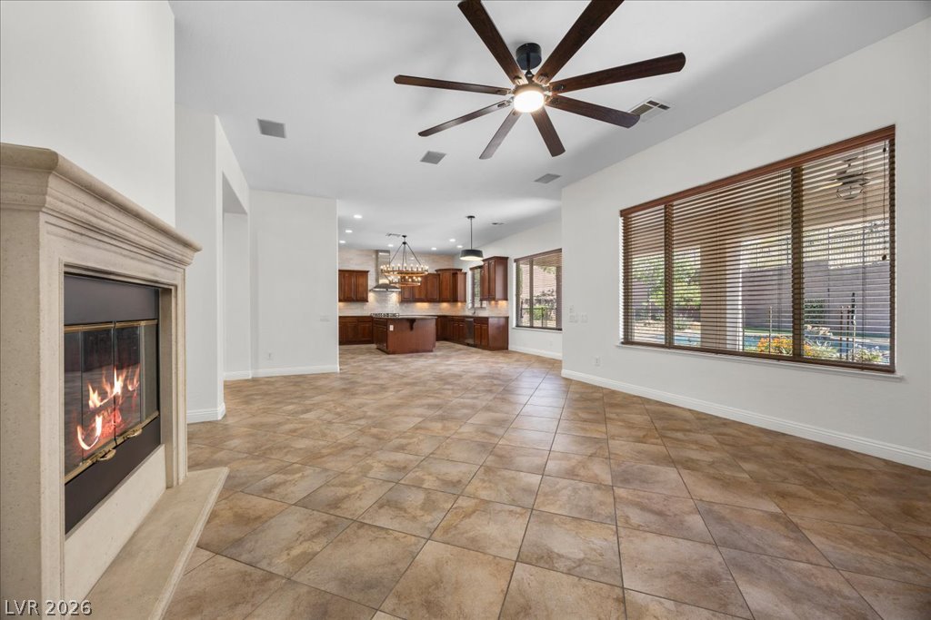 2125 De Rouge Avenue Henderson, NV 89044 - Photo 38 of 96 An inviting open-concept area connects a warm kitchen with ample cabinetry to a spacious living room featuring a cozy fireplace.