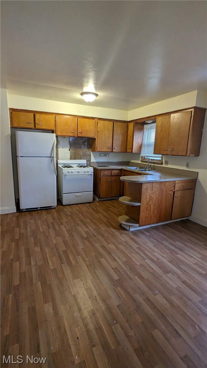 1470 Babbitt Road Euclid, OH 44117 - Photo 24 of 34 Kitchen featuring white appliances, kitchen peninsula, dark wood-type flooring, and sink