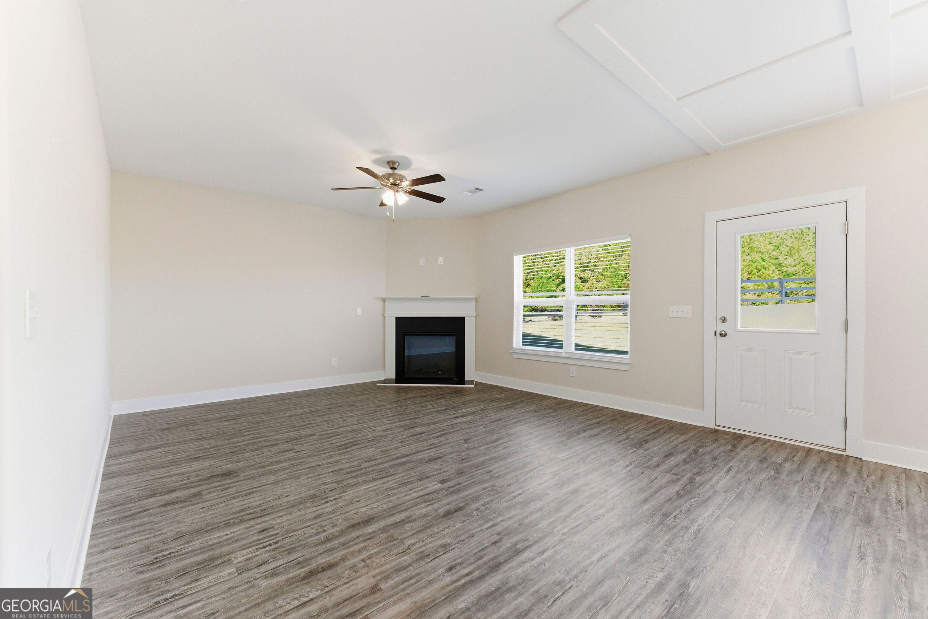 11209 Cornerstone Lane Hampton, GA 30228 - Photo 11 of 38 an empty room with windows chandelier fan and fireplace