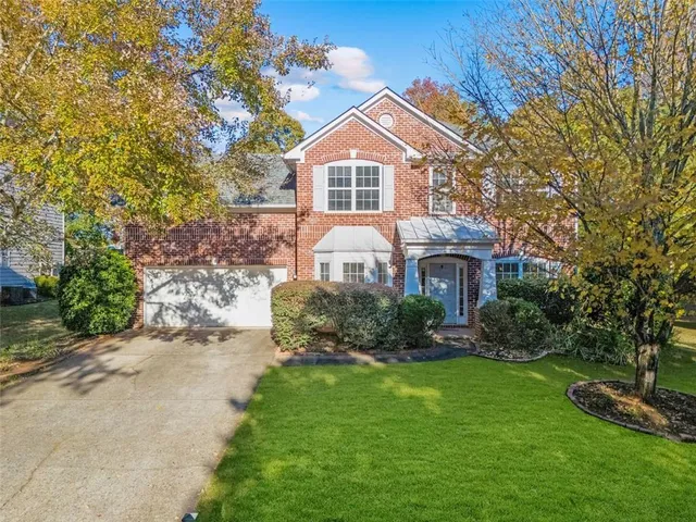 a front view of a house with a yard and potted plants
