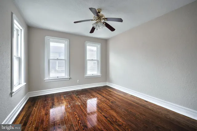 a view of empty room with wooden floor and fan