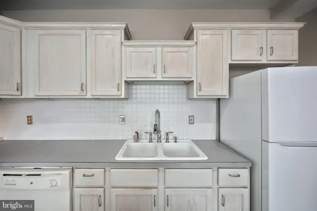 a kitchen with white cabinets and a refrigerator