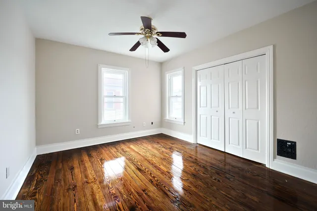 a view of empty room with wooden floor and fan