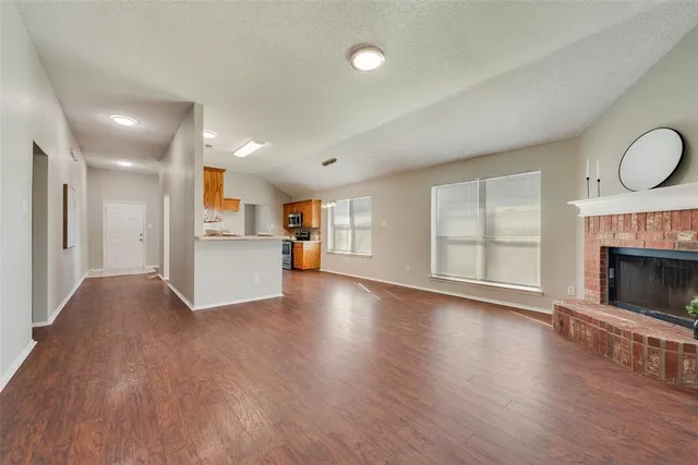 a view of empty room with wooden floor and fireplace