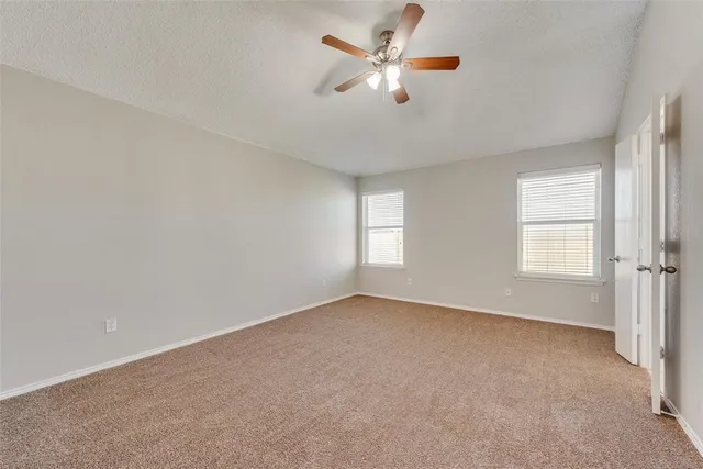 an empty room with windows and chandelier fan