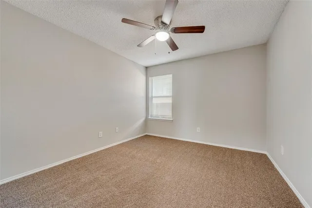 an empty room with a window and a ceiling fan