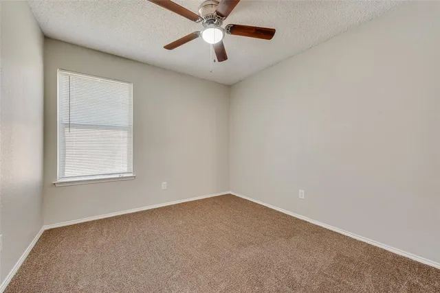 an empty room with ceiling fan and window