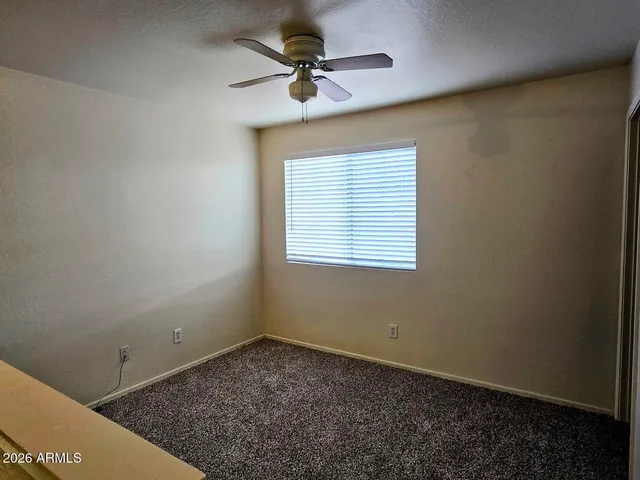 an empty room with a window and a ceiling fan
