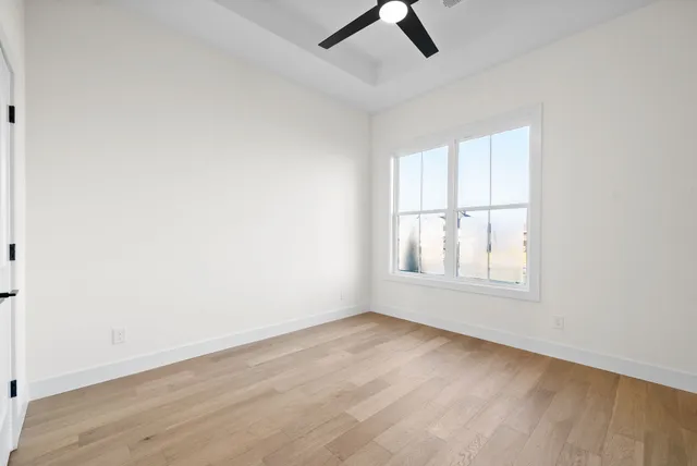an empty room with wooden floor cabinet and windows