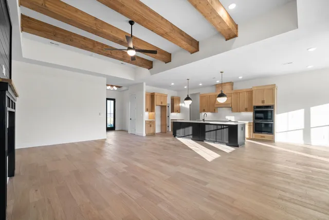 a view of kitchen with kitchen island granite countertop stainless steel appliances refrigerator oven cabinets and living room view
