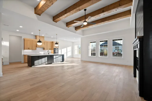 a view of an empty room with kitchen view and a window
