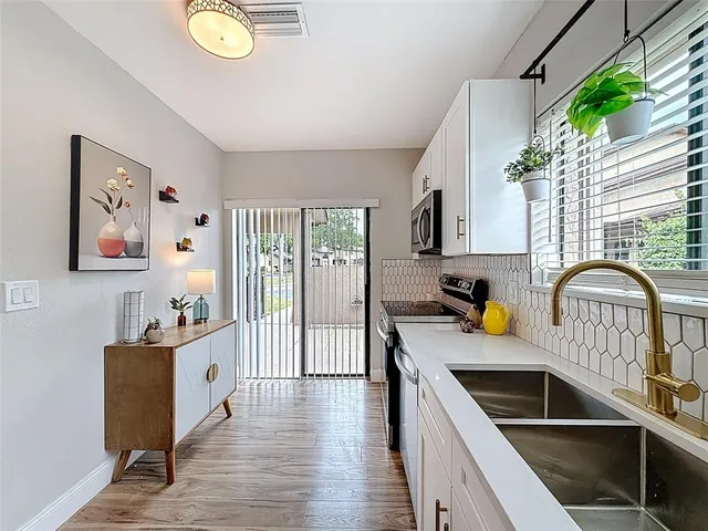 a kitchen that has a lot of cabinets a sink and wooden floor