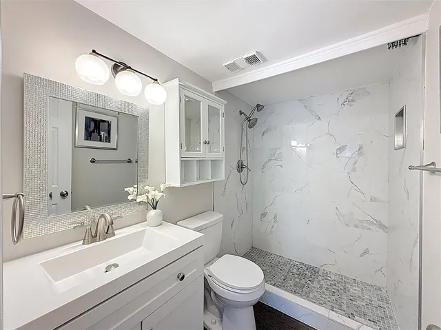 a bathroom with a sink toilet vanity and shower
